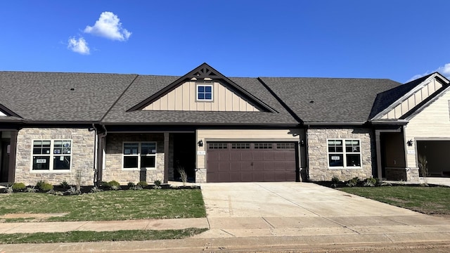 view of front facade with a garage, concrete driveway, stone siding, a front lawn, and board and batten siding