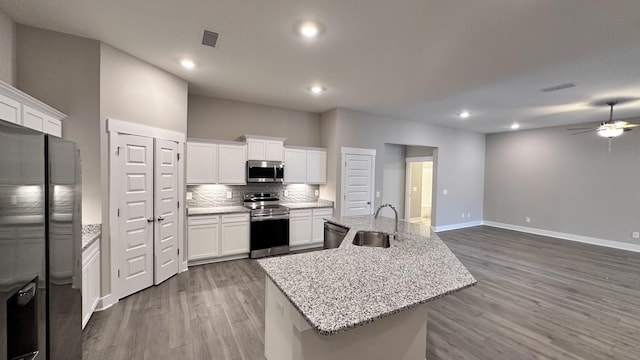 kitchen featuring wood finished floors, a sink, white cabinetry, appliances with stainless steel finishes, and tasteful backsplash