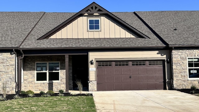 view of front of property with an attached garage, a shingled roof, stone siding, concrete driveway, and board and batten siding