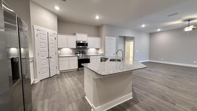 kitchen featuring decorative backsplash, an island with sink, appliances with stainless steel finishes, wood finished floors, and a sink