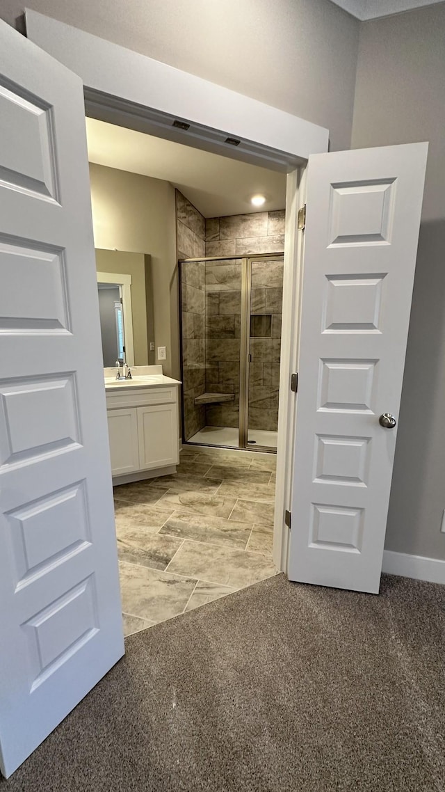 bathroom with a stall shower, vanity, and baseboards