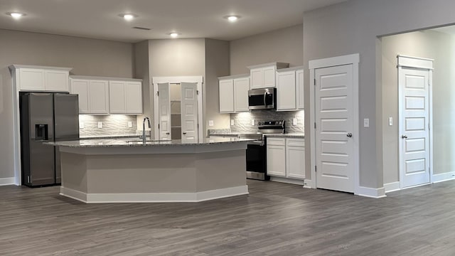 kitchen with stainless steel appliances, an island with sink, a sink, and white cabinetry