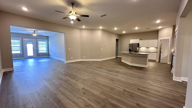 unfurnished living room with ceiling fan, recessed lighting, visible vents, baseboards, and dark wood finished floors