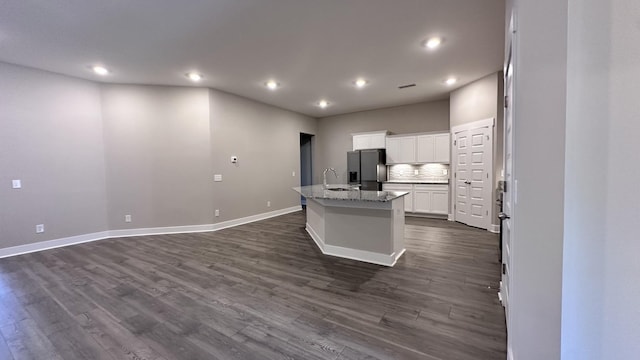 kitchen with dark wood-type flooring, a kitchen island with sink, fridge with ice dispenser, and white cabinetry