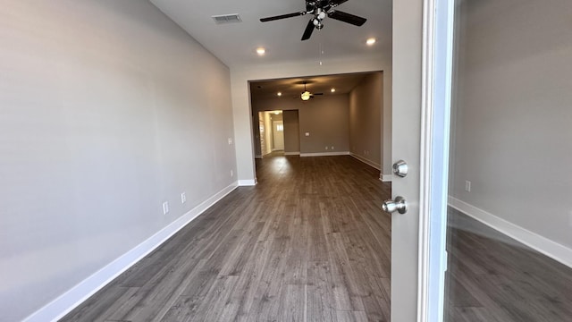 spare room with baseboards, visible vents, and dark wood-style flooring