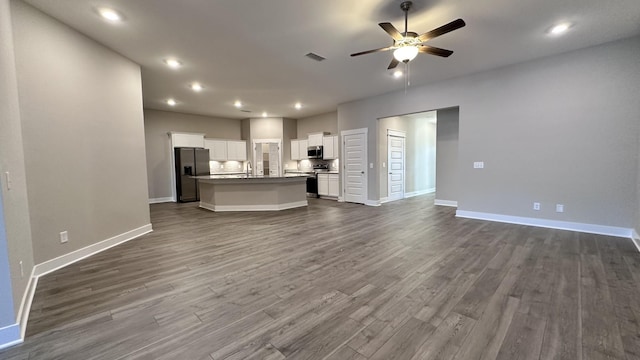 unfurnished living room with a ceiling fan, recessed lighting, dark wood-style flooring, and baseboards