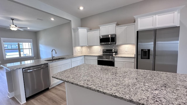 kitchen with tasteful backsplash, a peninsula, stainless steel appliances, white cabinetry, and a sink