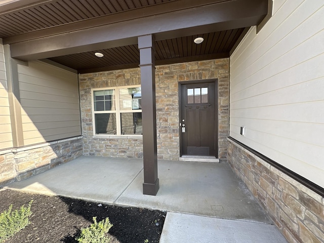 entrance to property featuring stone siding and a porch