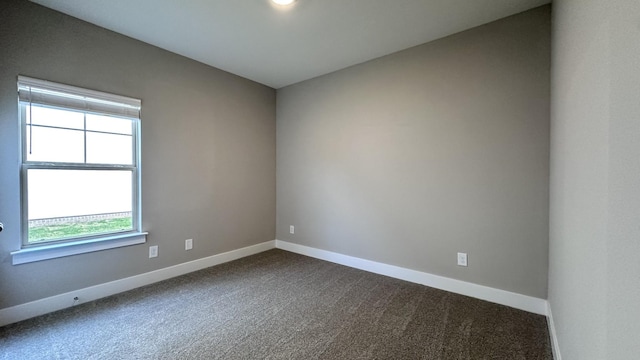 spare room featuring baseboards and dark colored carpet