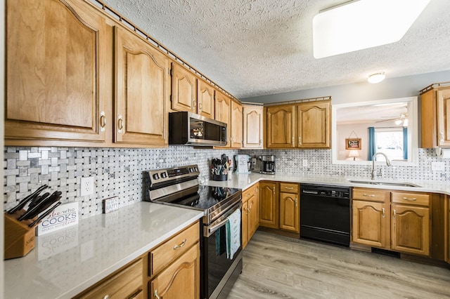 kitchen with stainless steel appliances, light countertops, a sink, and light wood-style flooring