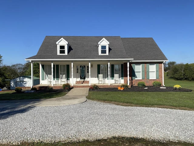 view of front of home featuring a front lawn, roof with shingles, a porch, and brick siding