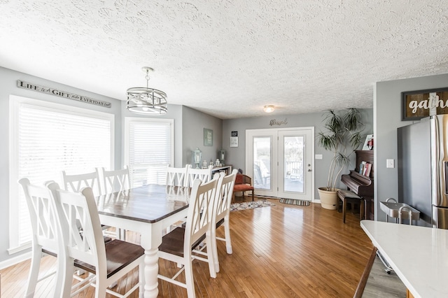 dining space featuring a notable chandelier, a textured ceiling, and light wood finished floors