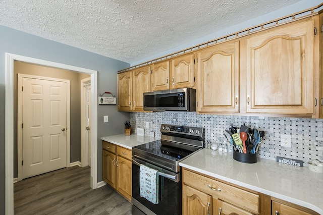 kitchen with light countertops, appliances with stainless steel finishes, dark wood-style flooring, and backsplash