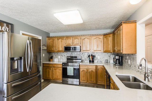 kitchen with brown cabinets, tasteful backsplash, light countertops, appliances with stainless steel finishes, and a sink