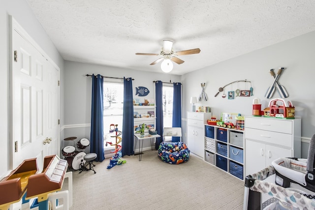 game room with carpet, ceiling fan, and a textured ceiling