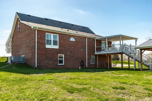 rear view of property with stairs, a yard, and brick siding