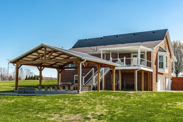 rear view of house with brick siding, a yard, stairway, an attached garage, and a gazebo