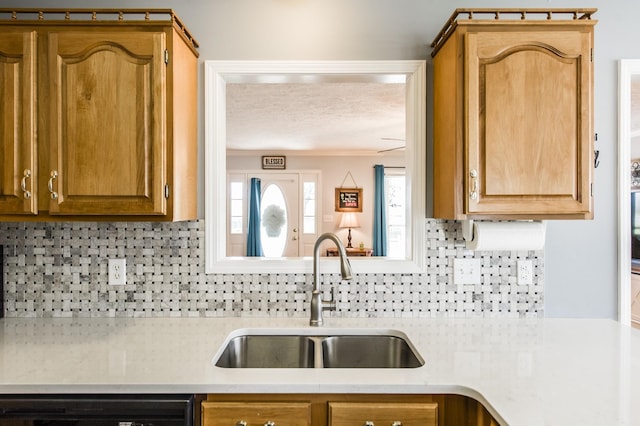 kitchen with a textured ceiling, a sink, light countertops, backsplash, and dishwasher