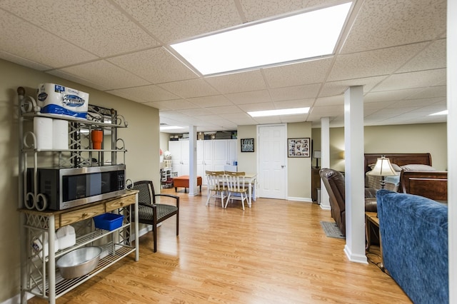 interior space with a drop ceiling, baseboards, and wood finished floors