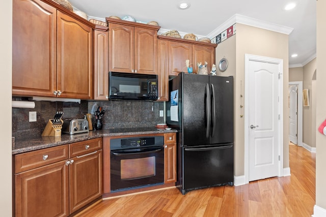 kitchen with light wood finished floors, black appliances, ornamental molding, and decorative backsplash