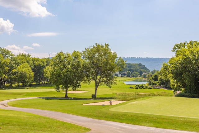 view of community with a water view, view of golf course, and a lawn