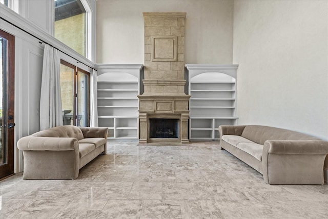 living room with a fireplace, a towering ceiling, a wealth of natural light, and built in features