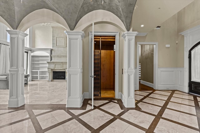 interior space featuring decorative columns, built in shelves, baseboards, and a fireplace