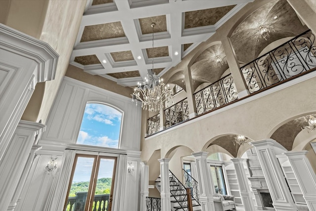 interior space with a high ceiling, beam ceiling, coffered ceiling, and decorative columns