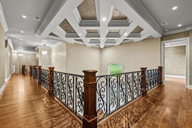 hallway with wood finished floors, coffered ceiling, an upstairs landing, and visible vents