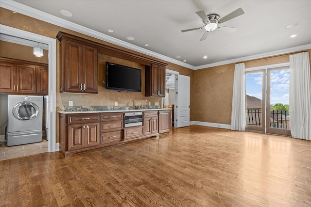 kitchen with ornamental molding, washer / clothes dryer, light countertops, and wood finished floors