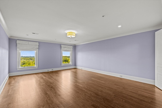 unfurnished room featuring baseboards, wood finished floors, visible vents, and crown molding