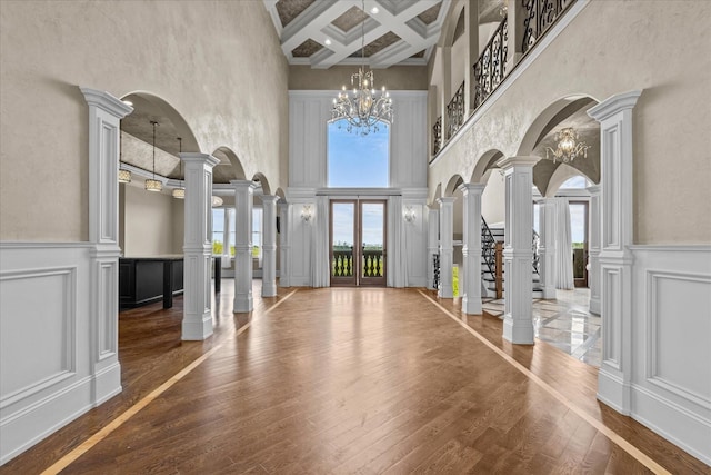 foyer entrance with a decorative wall, coffered ceiling, beam ceiling, and ornate columns