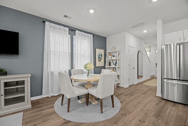 dining area featuring light wood-type flooring, visible vents, and baseboards