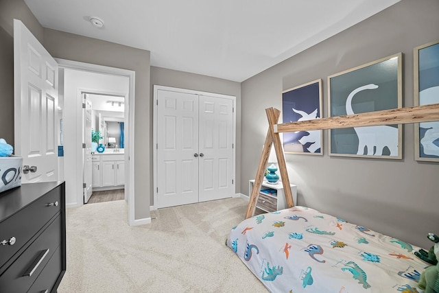 bedroom featuring connected bathroom, light colored carpet, a closet, and baseboards