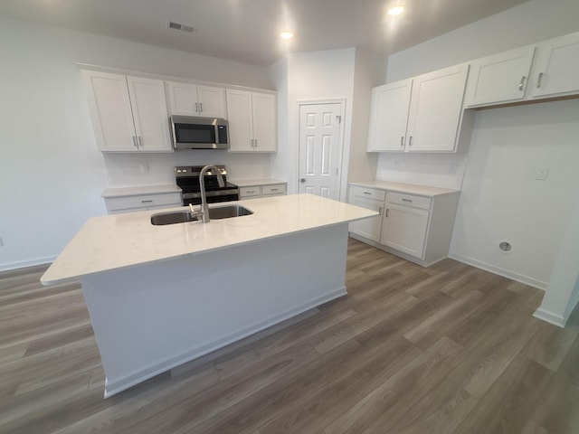 kitchen with a sink, visible vents, white cabinetry, appliances with stainless steel finishes, and dark wood finished floors