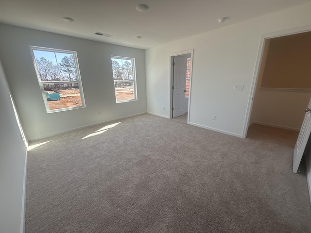 unfurnished bedroom featuring a spacious closet, light colored carpet, visible vents, and baseboards