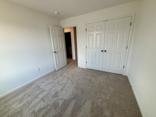 unfurnished bedroom with a closet, carpet flooring, and baseboards