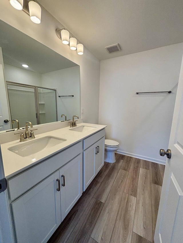 bathroom featuring a sink, visible vents, wood finished floors, and a shower stall