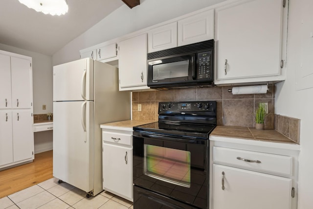 kitchen with light tile patterned floors, tasteful backsplash, white cabinetry, vaulted ceiling, and black appliances