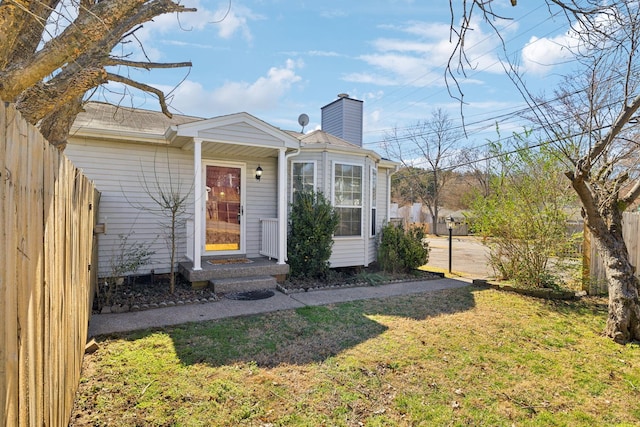 exterior space with a front yard, fence, and a chimney