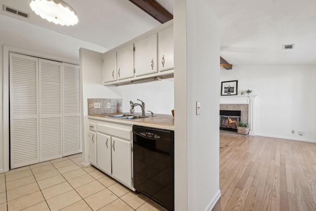 kitchen featuring dishwasher, light countertops, a sink, and visible vents