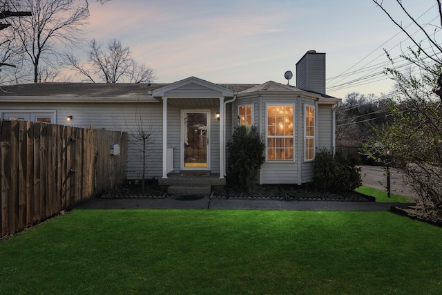 view of front of property with a yard, fence, and a chimney