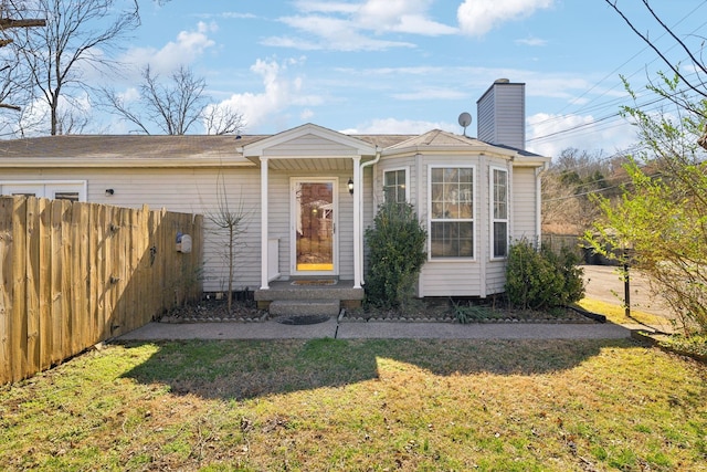 view of front of home with a front yard, fence, and a chimney