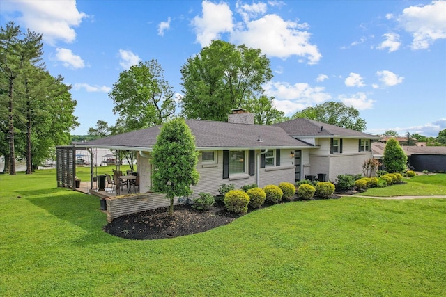 split level home with roof with shingles, a chimney, and a front yard