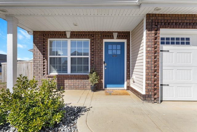 entrance to property featuring an attached garage and brick siding