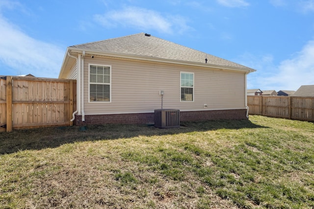 back of property featuring a shingled roof, a lawn, a fenced backyard, and central air condition unit