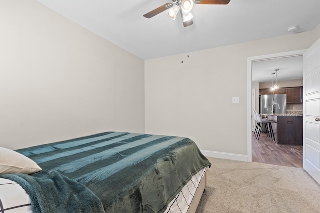 bedroom featuring a ceiling fan, carpet, stainless steel refrigerator with ice dispenser, and baseboards