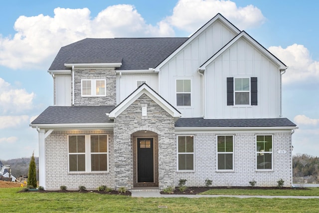 view of front of property with stone siding, a front lawn, board and batten siding, and brick siding