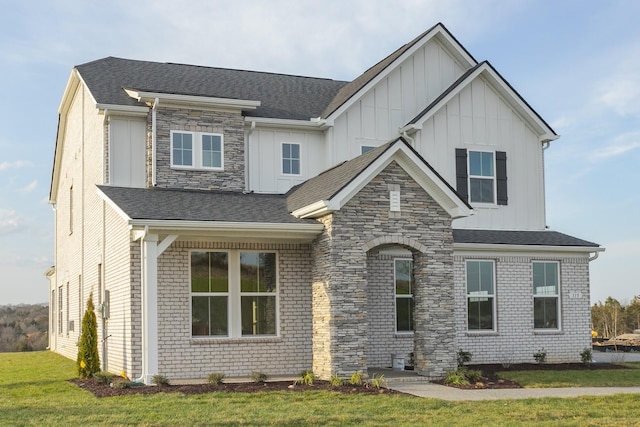 view of front of property featuring stone siding, roof with shingles, board and batten siding, and a front yard