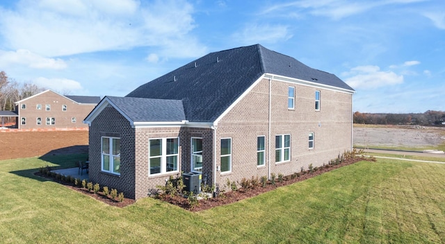 rear view of property featuring a yard, brick siding, a shingled roof, and cooling unit